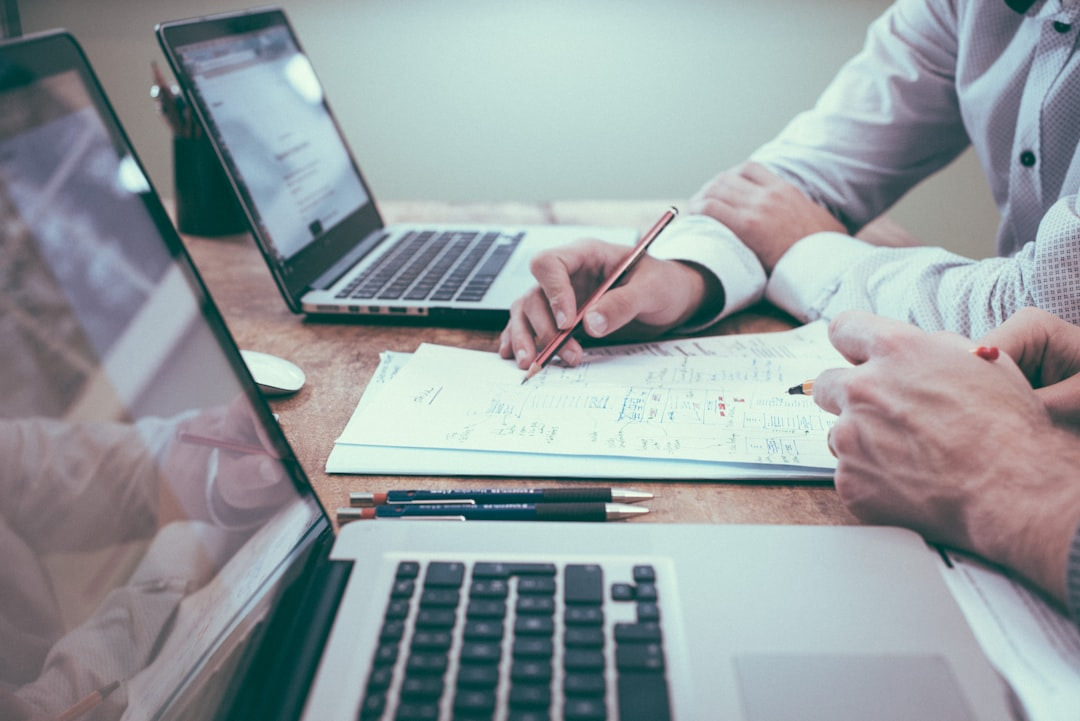 Mesa de trabalho com computador e documentos de análise imobiliária